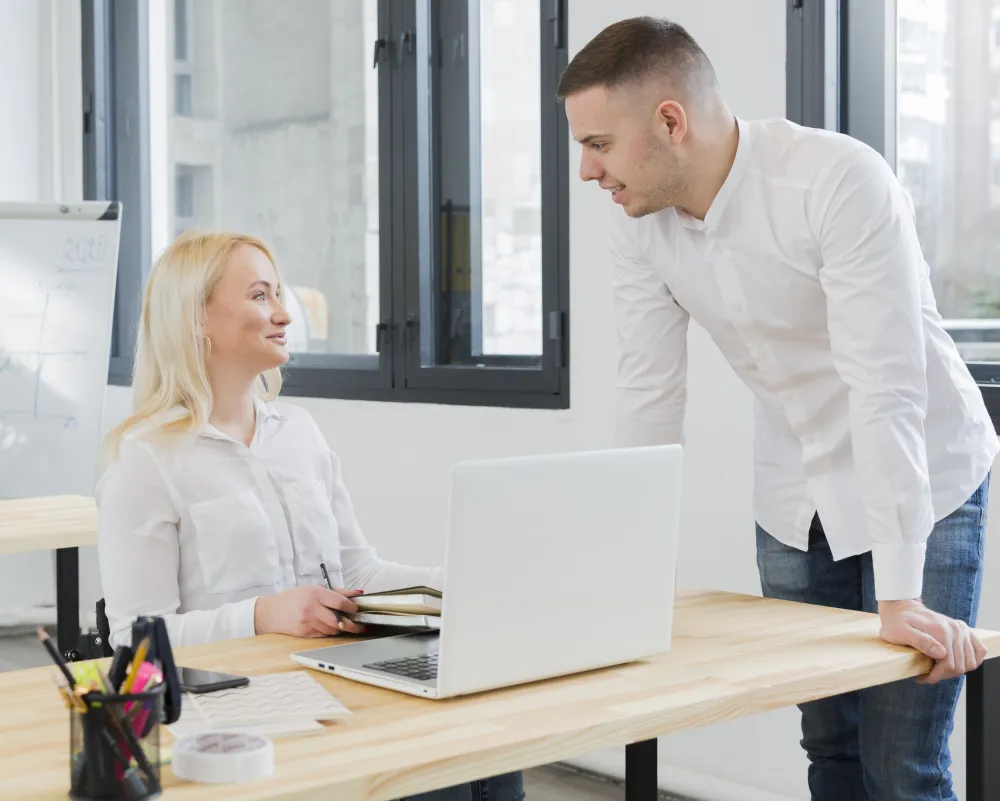 Frau im Rollstuhl unterhält sich im Büro mit einem Kollegen